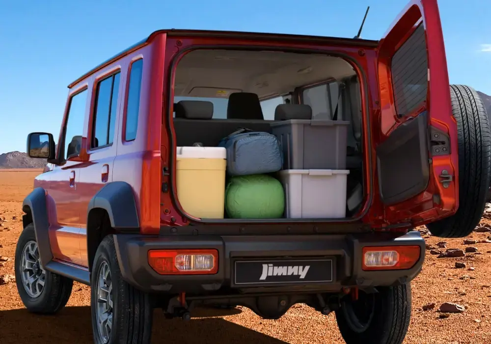 Suzuki Jimny rojo estacionado en el desierto con el portón trasero abierto.