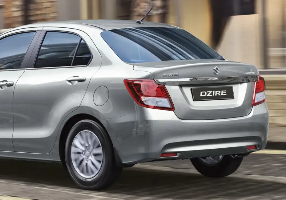 Vista trasera de un Suzuki Dzire plateado, modelo sedán compacto.