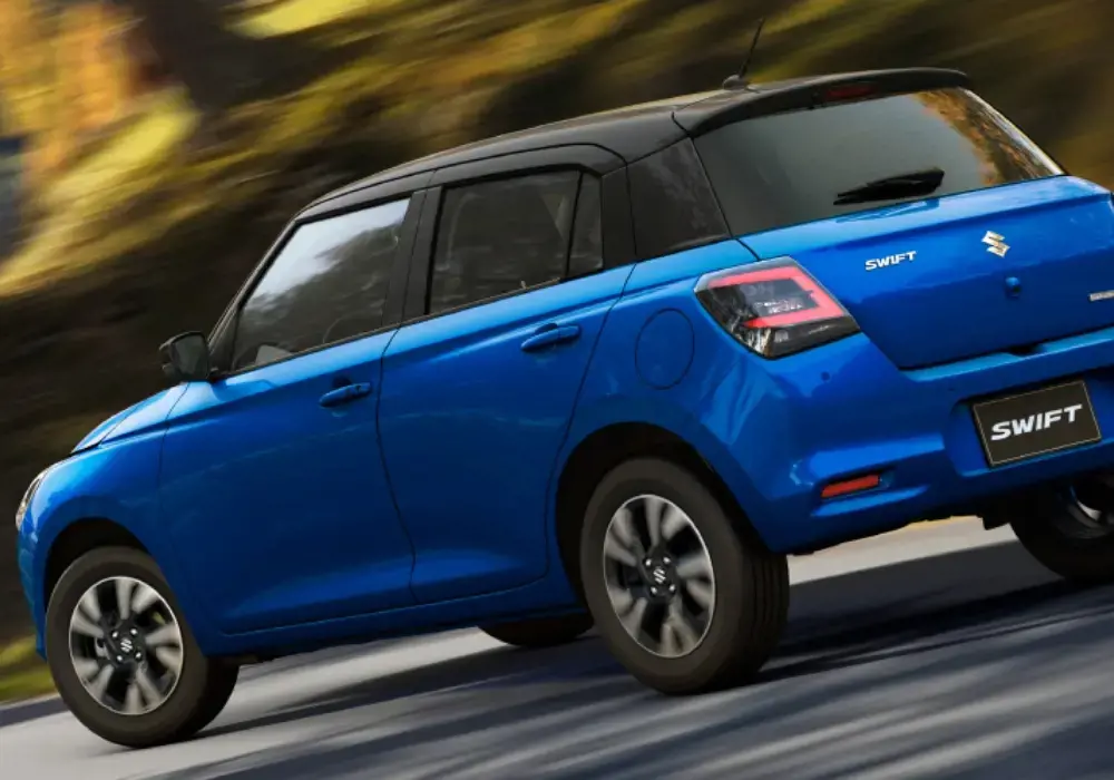 Suzuki Swift Híbrido azul metálico con techo negro circula por una carretera
