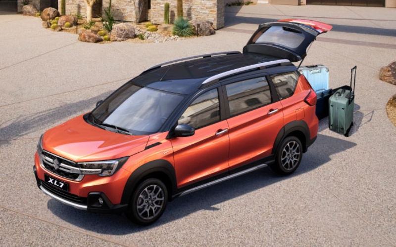 Suzuki XL7 híbrido naranja estacionado y con el maletero abierto.