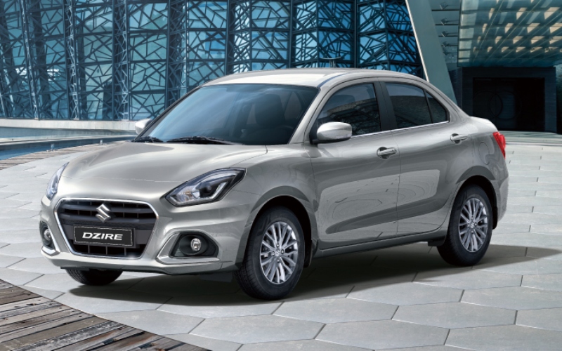 Suzuki Dzire plateado estacionado en plaza pública